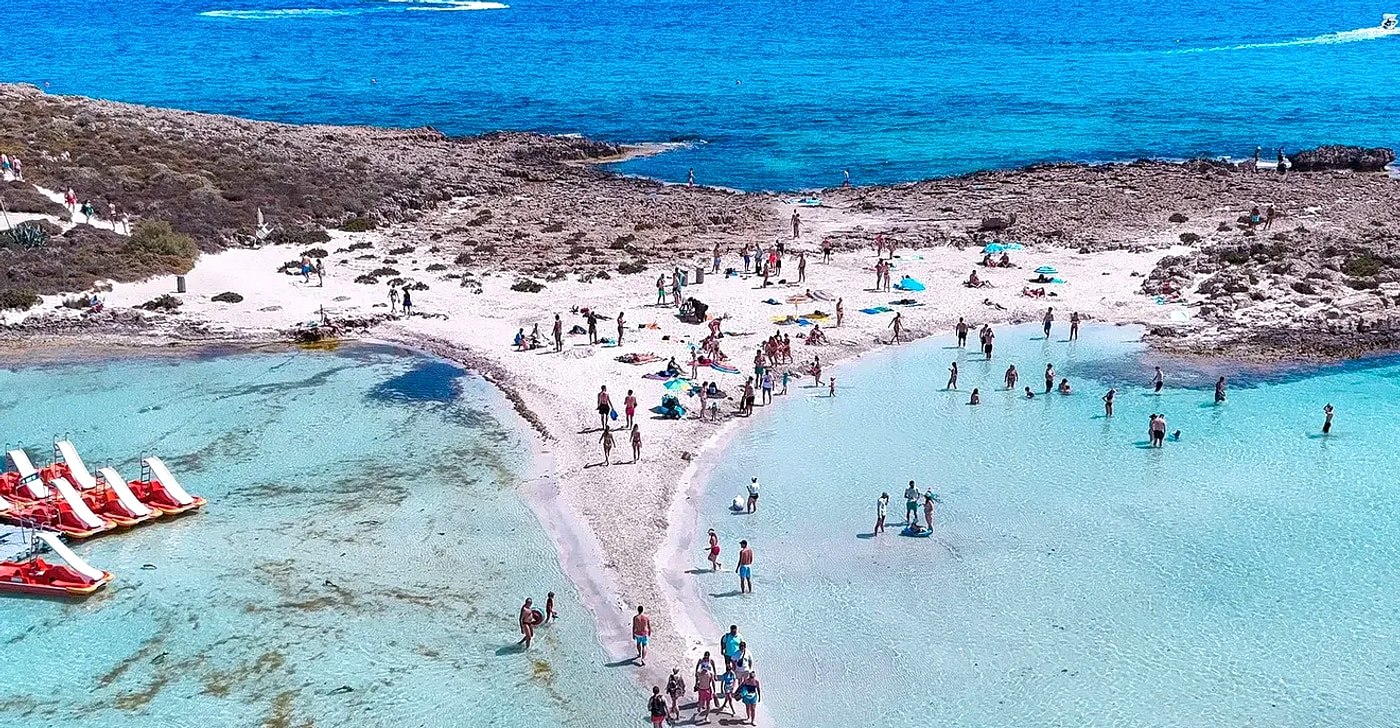 Nissi Beach in Ayia Napa: pale sand, shallow turquoise water and the sandbar leading across to the rocky islet